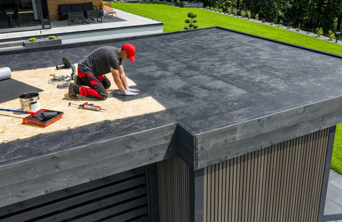 Worker fitting EPDM rubber membrane to a flat roof